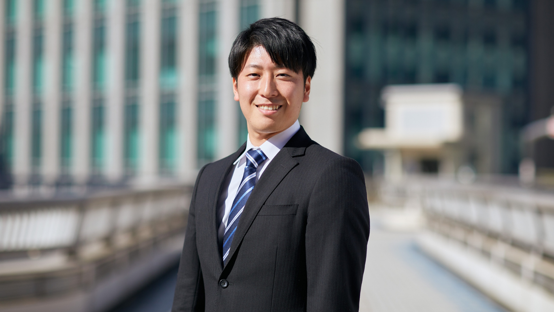 屋外で微笑むスーツ姿の若い男性