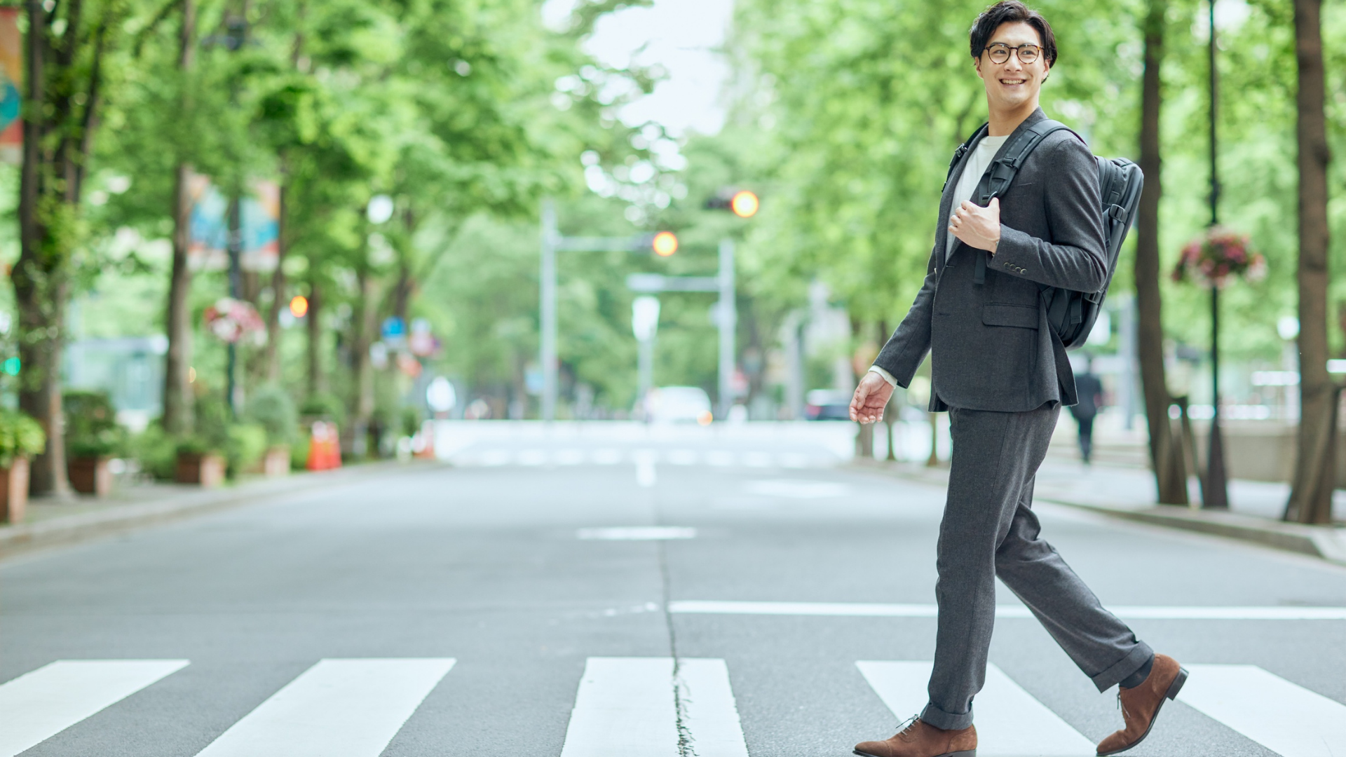 バックパックを背負い横断歩道を渡るスーツ姿の男性