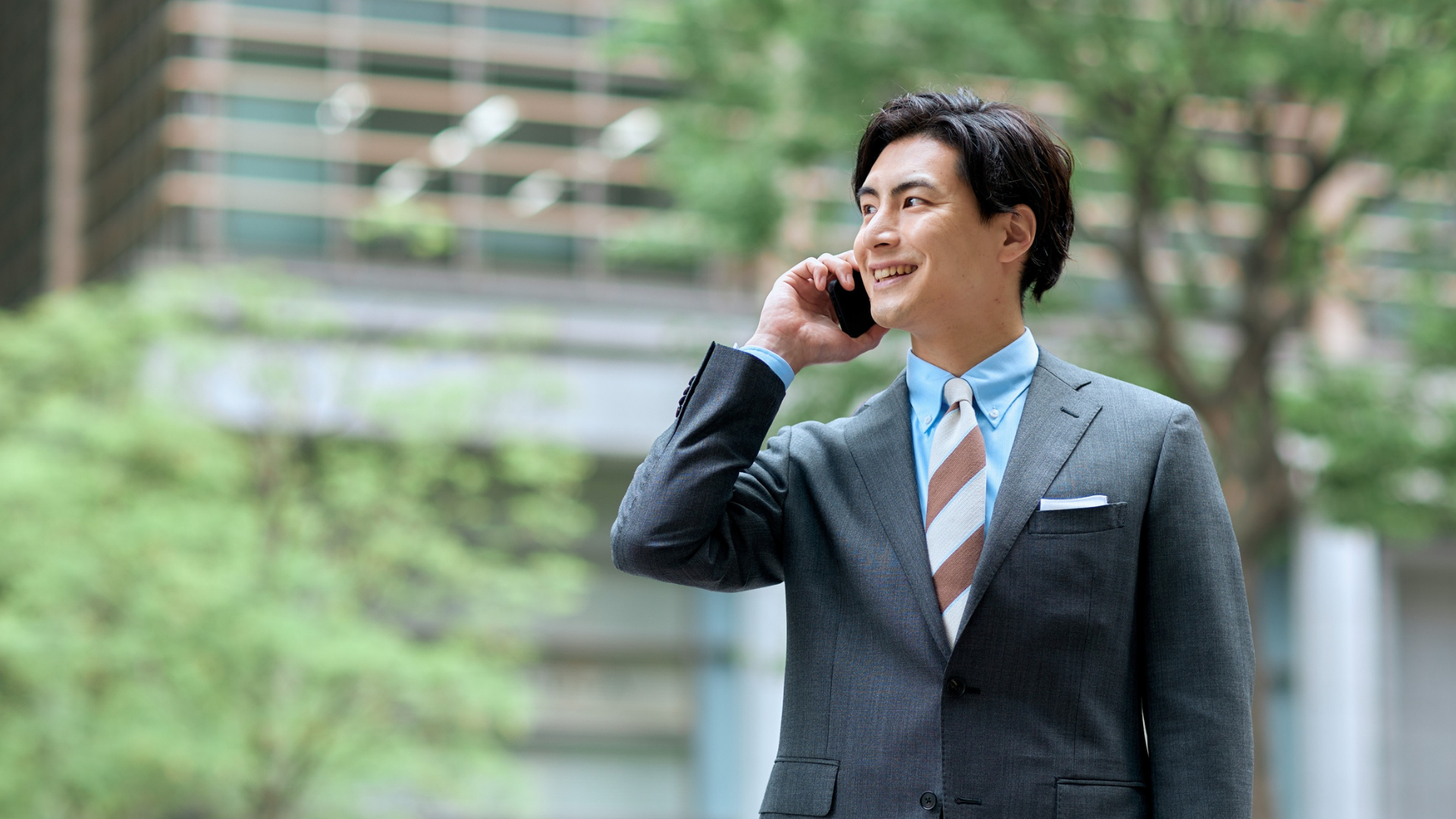 屋外で爽やかに微笑むスーツ姿の若い男性