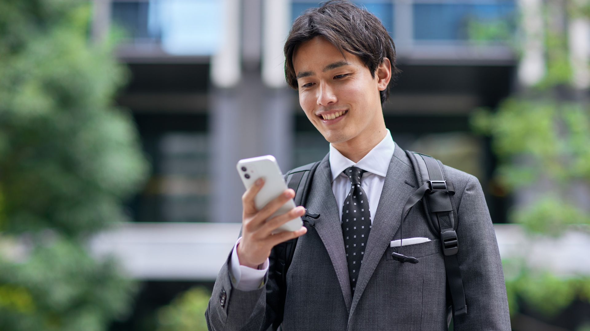 屋外でスマートフォンを持つバックパックの男性