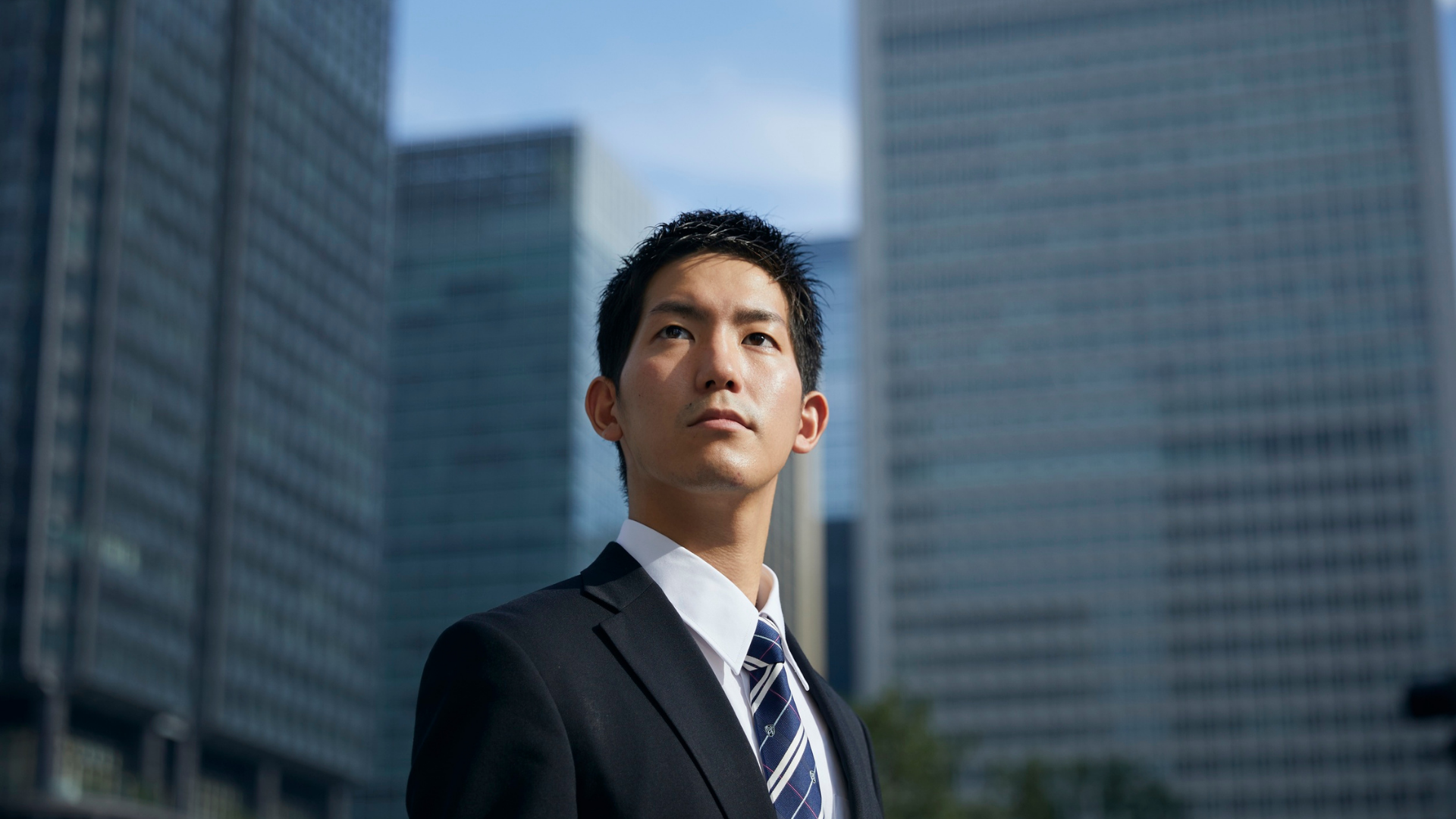 高層ビルを見上げるスーツ姿の男性