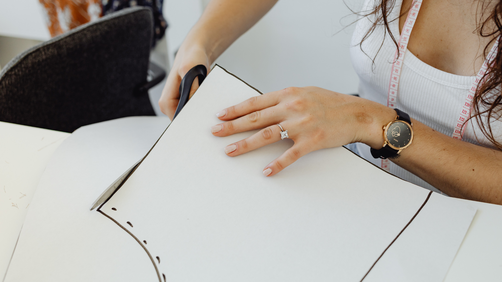 型紙をハサミでカットする女性テーラーの手元